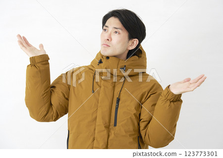A man wearing a down jacket is astonished on a white background A man wearing a down jacket is astonished on a white background 123773301