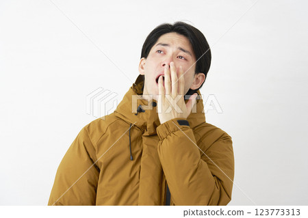 Man wearing down jacket yawning white background Man wearing down jacket yawning white background 123773313