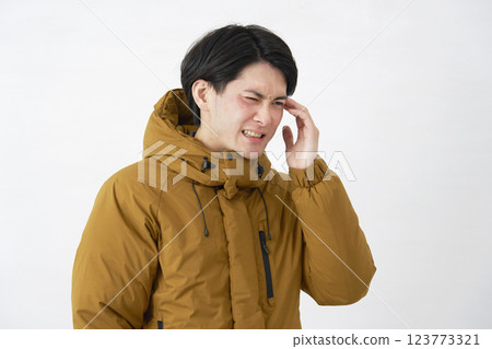 Man wearing down jacket, headache, white background 123773321