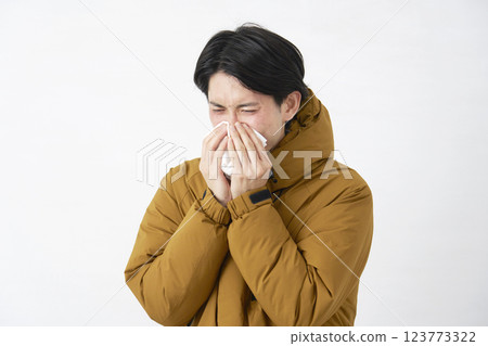 Man wearing a down jacket blowing his nose on white background 123773322