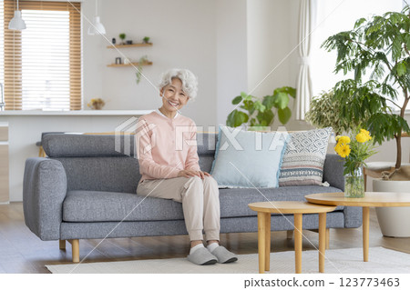Smiling senior woman looking at camera while sitting on sofa at home Smiling senior woman looking at camera while sitting on sofa at home 123773463