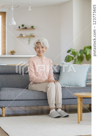 Smiling senior woman looking at camera while sitting on sofa at home 123773605