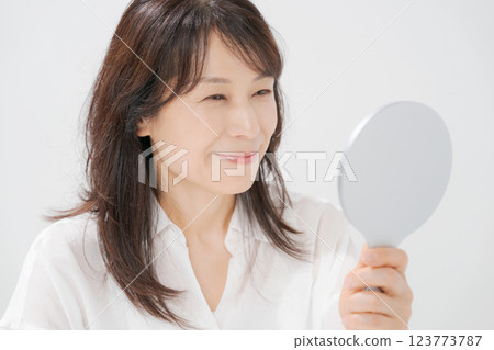 Smiling middle-aged woman holding a hand mirror Smiling middle-aged woman holding a hand mirror 123773787