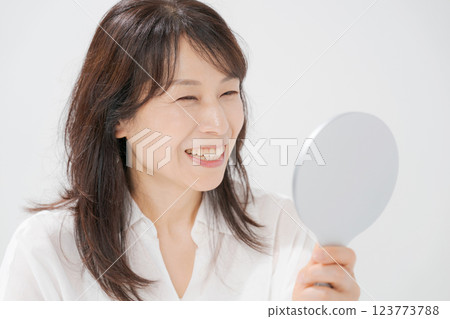 Smiling middle-aged woman holding a hand mirror Smiling middle-aged woman holding a hand mirror 123773788