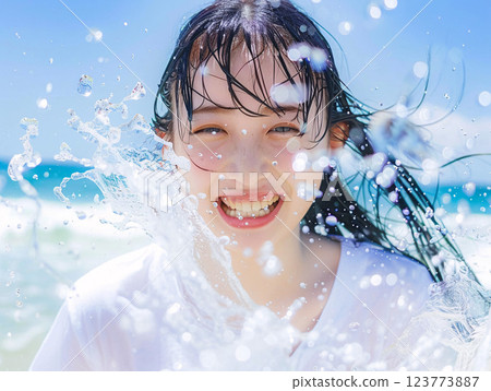 Smiling Asian woman enjoying playing in the water at the beach 123773887