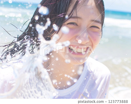 Smiling Asian woman enjoying playing in the water at the beach 123773888
