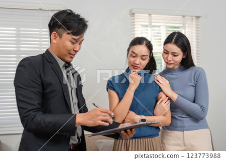 Real estate agent writing down information while two potential buyers look on in a modern setting. Real estate agent writing down information while two potential buyers look on in a modern setting. 123773988