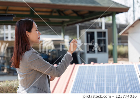 Sustainable business initiative. Female professional examining solar panels for renewable energy project. 123774010