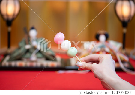 Woman's hands holding a Hina doll and dumplings 123774025