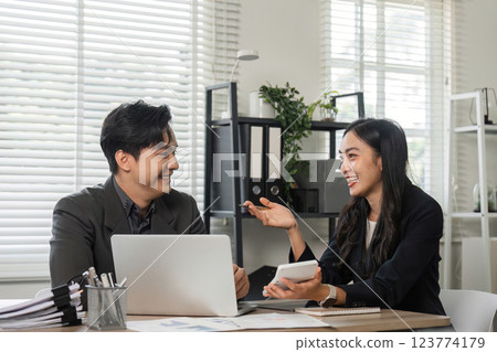 Diverse business partners smiling and discussing financial strategies in a modern office. Diverse business partners smiling and discussing financial strategies in a modern office. 123774179