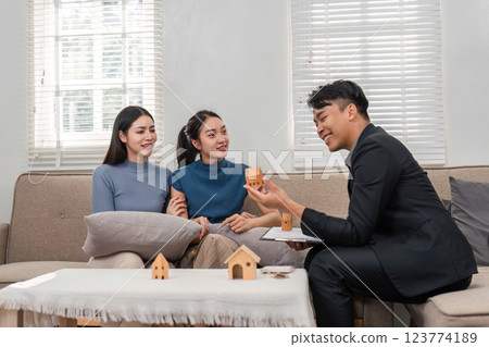 Real estate agent showcasing miniature houses to prospective buyers in a stylish setting. 123774189