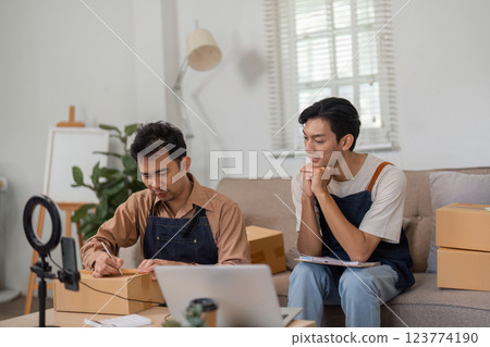 Dynamic duo of online sellers reviewing their business progress in a cozy living room. 123774190