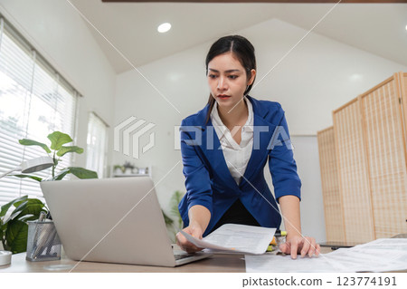 Professional accountant reviewing financial documents on a laptop Professional accountant reviewing financial documents on a laptop 123774191