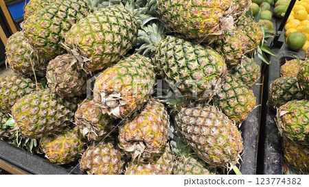 Fresh Pineapples in a Vibrant Market Display of Tropical Fruits, Colorful display of fresh, ripe pineapples at a market showcasing a tropical atmosphere 123774382