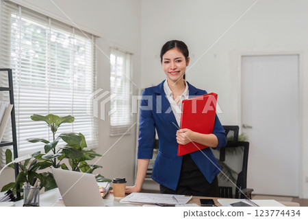 Businesswoman reviewing financial documents in a modern office setting, showcasing professionalism and organization. Businesswoman reviewing financial documents in a modern office setting, showcasing professionalism and organization. 123774434