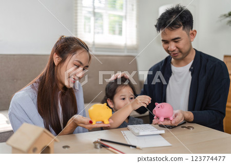Happy family teaching child about saving money with piggy banks and calculator. 123774477