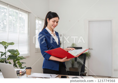 Professional woman examining financial reports in a stylish office, emphasizing diligence and attention to detail. 123774568