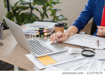 Accountant working on laptop and organizing financial documents 123774574