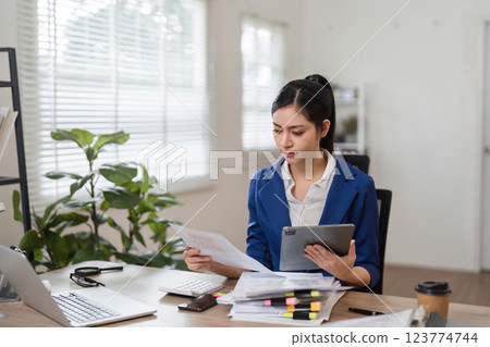 Professional accountant reviewing financial documents in a modern office setting. 123774744