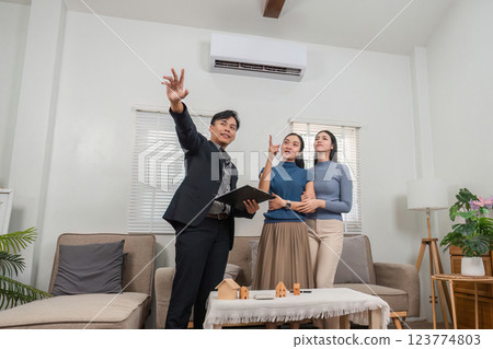 Real estate agent presenting property options to potential buyers in a modern living room. Real estate agent presenting property options to potential buyers in a modern living room. 123774803