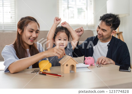 Family celebrating savings milestones with piggy banks and financial goals Family celebrating savings milestones with piggy banks and financial goals 123774828