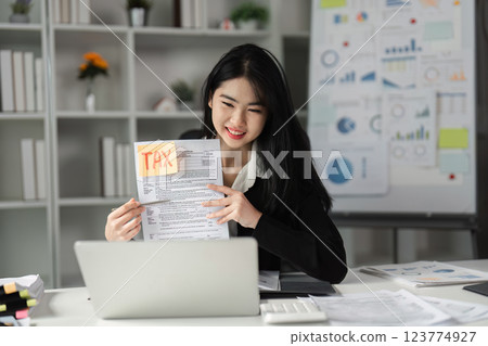 Businesswoman showcasing tax documents in a modern office setting. 123774927