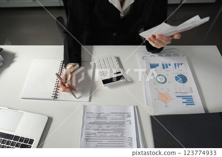 Accountant reviewing financial documents and taking notes with a calculator. 123774933