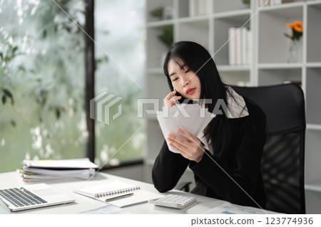 Accountant on the phone while reviewing financial documents. Accountant on the phone while reviewing financial documents. 123774936