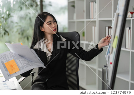 Accountant analyzing tax documents and financial charts in a modern office setting. 123774979