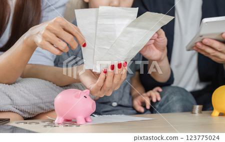 Family analyzing bills together, focusing on savings and expenses 123775024