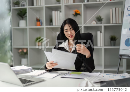 Professional woman analyzing financial documents in a modern office. 123775042