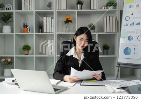Accountant reviewing financial reports and documents in a modern office setting, focusing on tax preparation. Accountant reviewing financial reports and documents in a modern office setting, focusing on tax preparation. 123775050