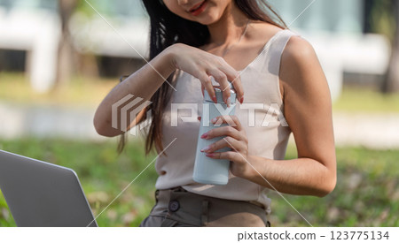 Eco-conscious habits. Woman opening a reusable water bottle while enjoying nature. Eco-conscious habits. Woman opening a reusable water bottle while enjoying nature. 123775134