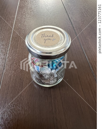 一罐巧克力,上面貼著感謝貼紙,放在木頭上 一罐巧克力,上面貼著感謝貼紙,放在木頭上 123775161