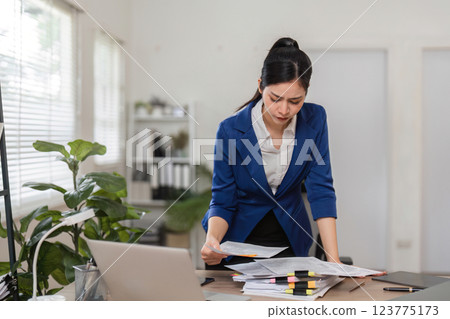 Accountant analyzing financial paperwork in a contemporary workspace, ensuring accurate tax filing. Accountant analyzing financial paperwork in a contemporary workspace, ensuring accurate tax filing. 123775173
