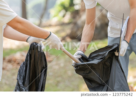 Volunteers collecting trash during a park cleanup, highlighting the importance of community involvement in environmental efforts. 123775242