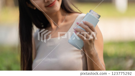 Sustainable choices. Woman holding a reusable bottle in a natural setting. Sustainable choices. Woman holding a reusable bottle in a natural setting. 123775292