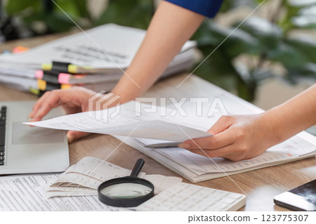 Close-up of accountant's hands sorting tax documents on a desk. 123775307