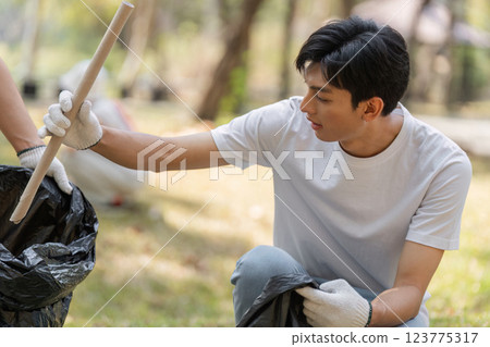 Volunteer focusing on proper waste disposal during a park cleanup, promoting eco-friendly practices and sustainability. Volunteer focusing on proper waste disposal during a park cleanup, promoting eco-friendly practices and sustainability. 123775317