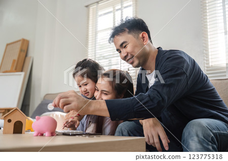Family enjoying savings activity together, teaching children about money management Family enjoying savings activity together, teaching children about money management 123775318