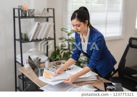 Diligent accountant organizing tax paperwork in a contemporary office, focusing on financial accuracy. Diligent accountant organizing tax paperwork in a contemporary office, focusing on financial accuracy. 123775321