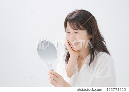 Smiling middle-aged woman holding a hand mirror 123775323
