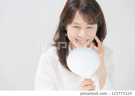 Smiling middle-aged woman holding a hand mirror 123775324