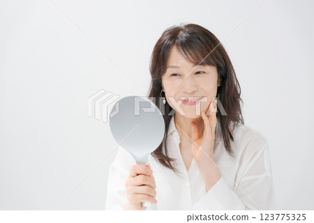 Smiling middle-aged woman holding a hand mirror 123775325