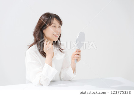 Smiling middle-aged woman holding a hand mirror Smiling middle-aged woman holding a hand mirror 123775328