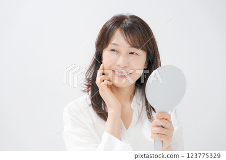 Smiling middle-aged woman holding a hand mirror 123775329