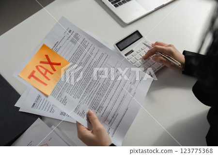 Businesswoman preparing tax documents and calculations at her desk. 123775368
