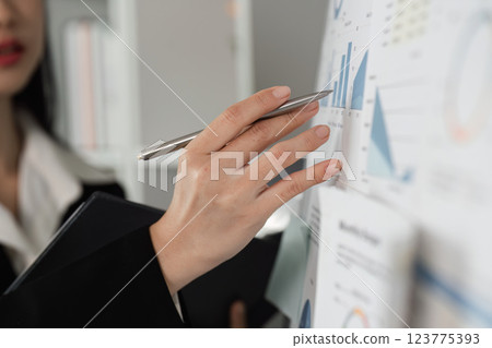Accountant analyzing financial data on a wall chart, emphasizing key metrics and insights. Accountant analyzing financial data on a wall chart, emphasizing key metrics and insights. 123775393