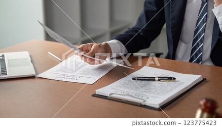 Lawyer examining contract documents with pen and laptop on desk in modern office. 123775423