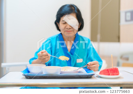 Senior Woman eating food after eye surgery in hospital . Eye disease, Cataract, Glaucoma, Age Related Macular Degeneration, Diabetic Retinopathy, Lasik, World Glaucoma day and health treatment Senior Woman eating food after eye surgery in hospital . Eye disease, Cataract, Glaucoma, Age Related Macular Degeneration, Diabetic Retinopathy, Lasik, World Glaucoma day and health treatment 123775663